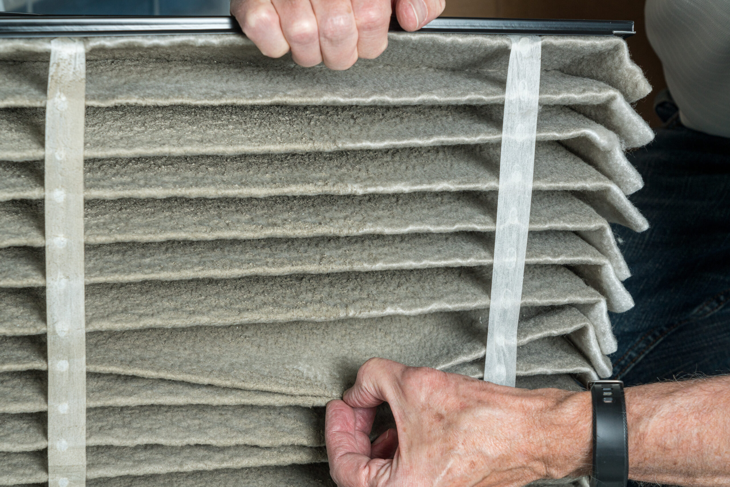 Senior man changing a dirty air filter in a HVAC Furnace